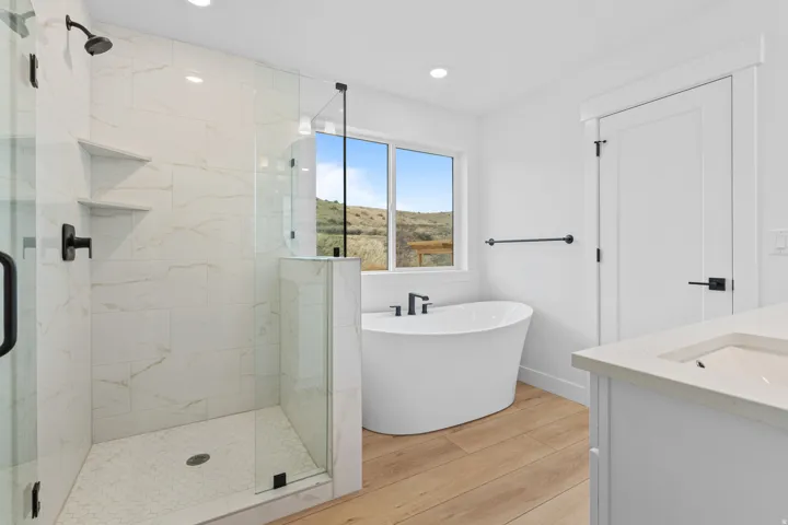 Full bath featuring a marble finish shower, a freestanding tub, light wood-style flooring, vanity, and recessed lighting