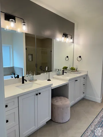 Full bath with double vanity, a shower stall, light tile patterned floors, and a bath