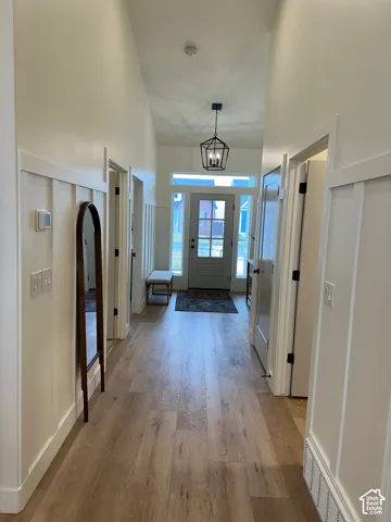 Foyer with light wood-style flooring, a high ceiling, a chandelier, and arched walkways