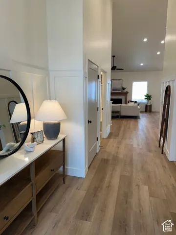 Hall with light wood-style floors, recessed lighting, and a decorative wall