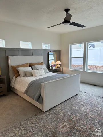 Carpeted bedroom featuring a ceiling fan and a textured ceiling