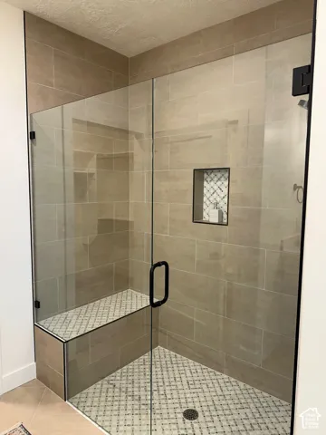 Full bath with a shower stall, tile patterned flooring, and a textured ceiling