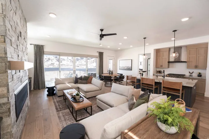 Living area with a fireplace, dark wood finished floors, and a ceiling fan