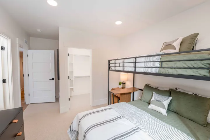 Bedroom with a spacious closet, light colored carpet, and recessed lighting