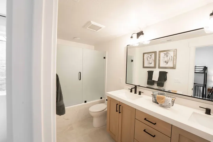 Bathroom with bath / shower combo with glass door and double vanity