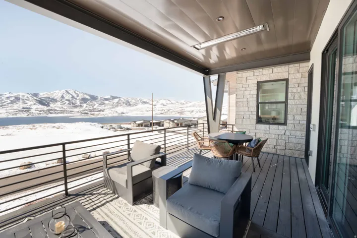 Snow covered back of property with outdoor dining space, a patio area, and a mountain view