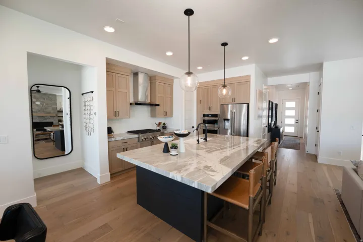 Kitchen with light wood-style flooring, a center island with sink, stainless steel appliances, a breakfast bar, and light stone countertops