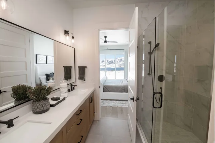 Ensuite bathroom featuring a stall shower, double vanity, light tile patterned flooring, and ceiling fan