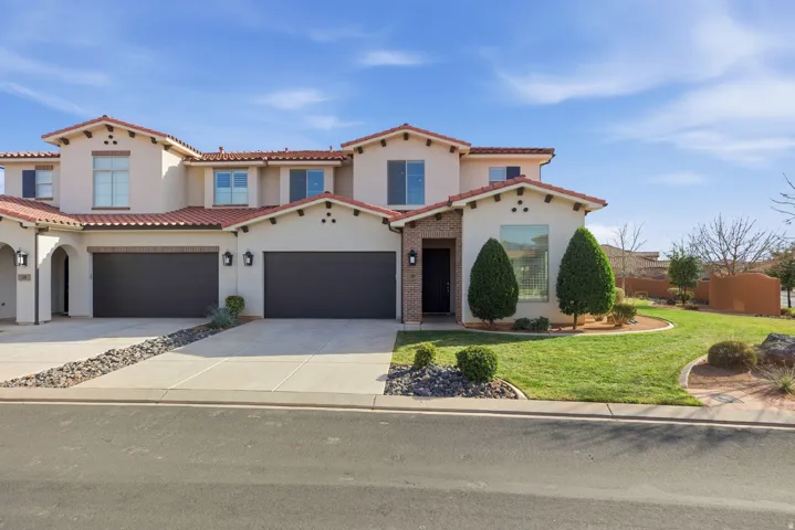 Mediterranean / spanish-style home with concrete driveway, a front yard, stucco siding, and a tile roof