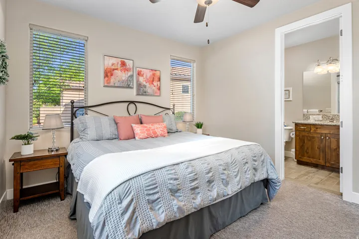 Casita bedroom featuring light colored carpet, ceiling fan, and ensuite bath