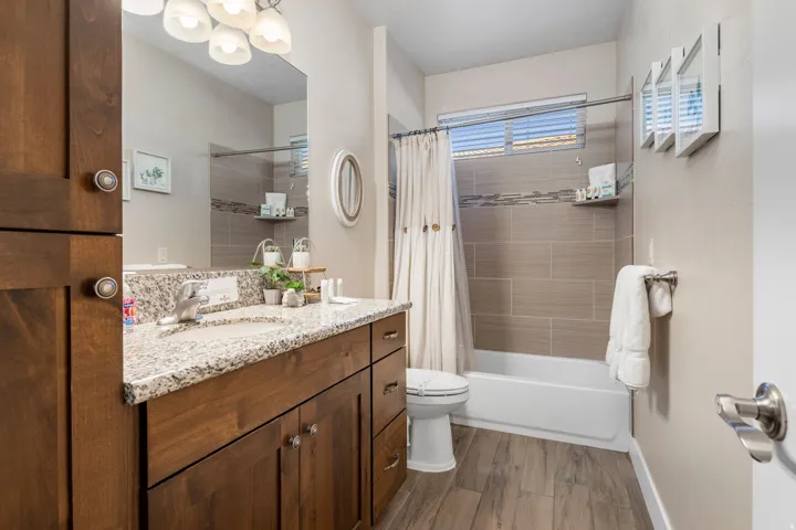 Bathroom with vanity, dark wood-style floors, and shower / bathtub combination with curtain