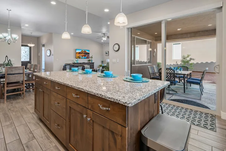 Kitchen with a kitchen island, light stone countertops, wood tiled floors, and ceiling fan