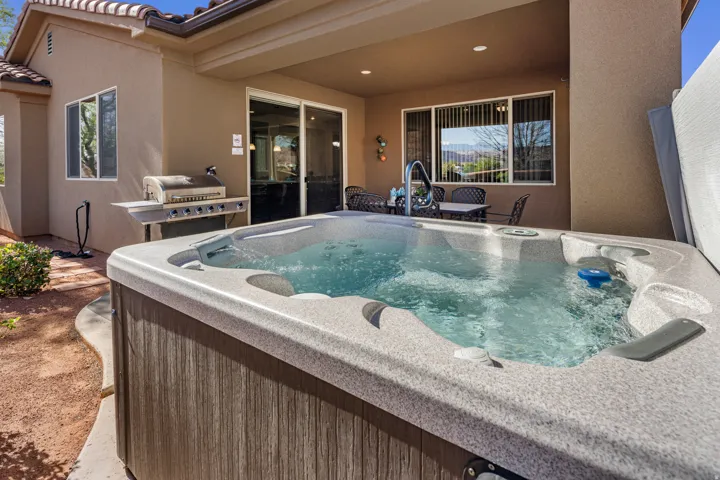 View of pool with patio surround, a hot tub, and grilling area