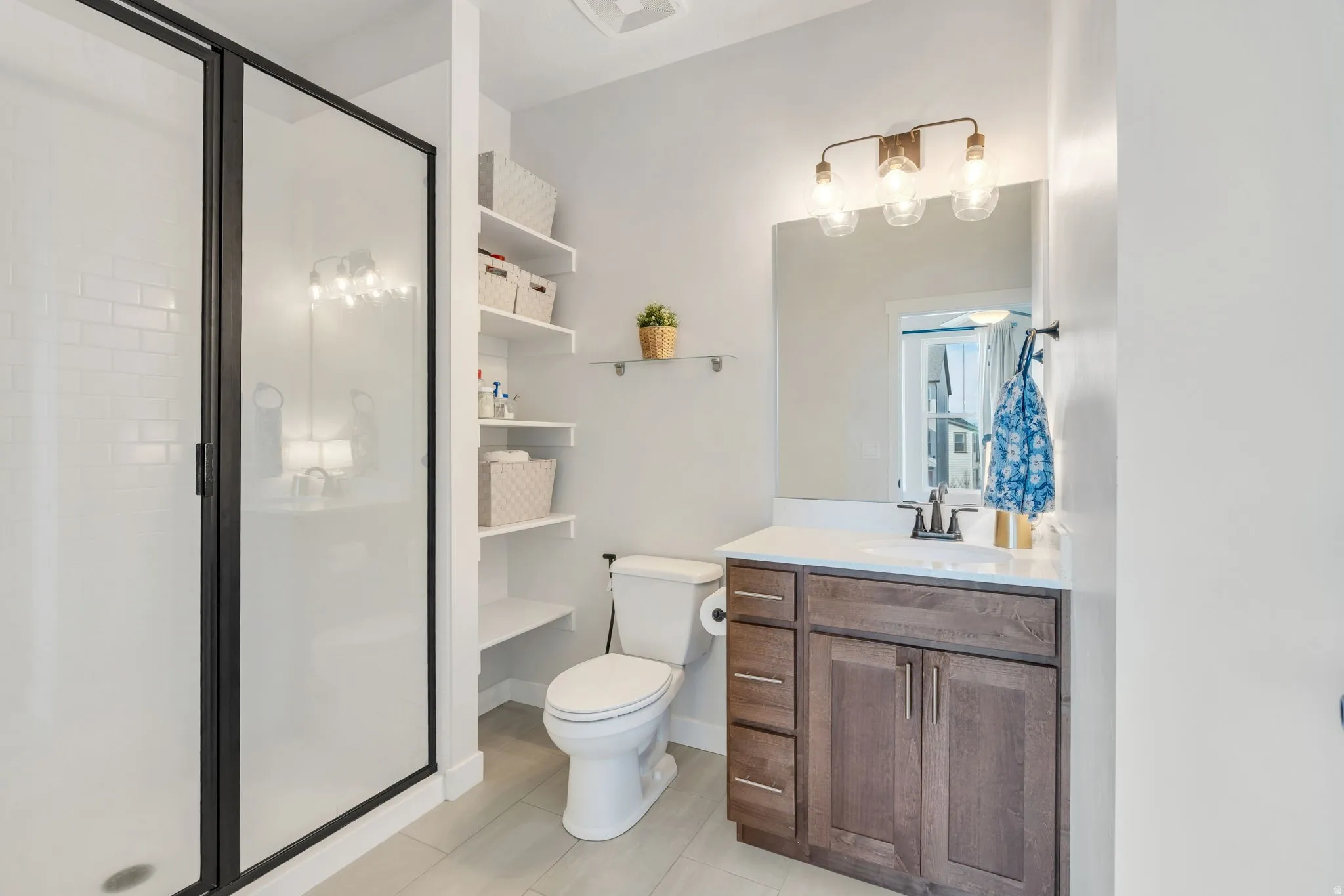 Pristine bathroom featuring a walk-in shower, ample built in shelves, and vanity