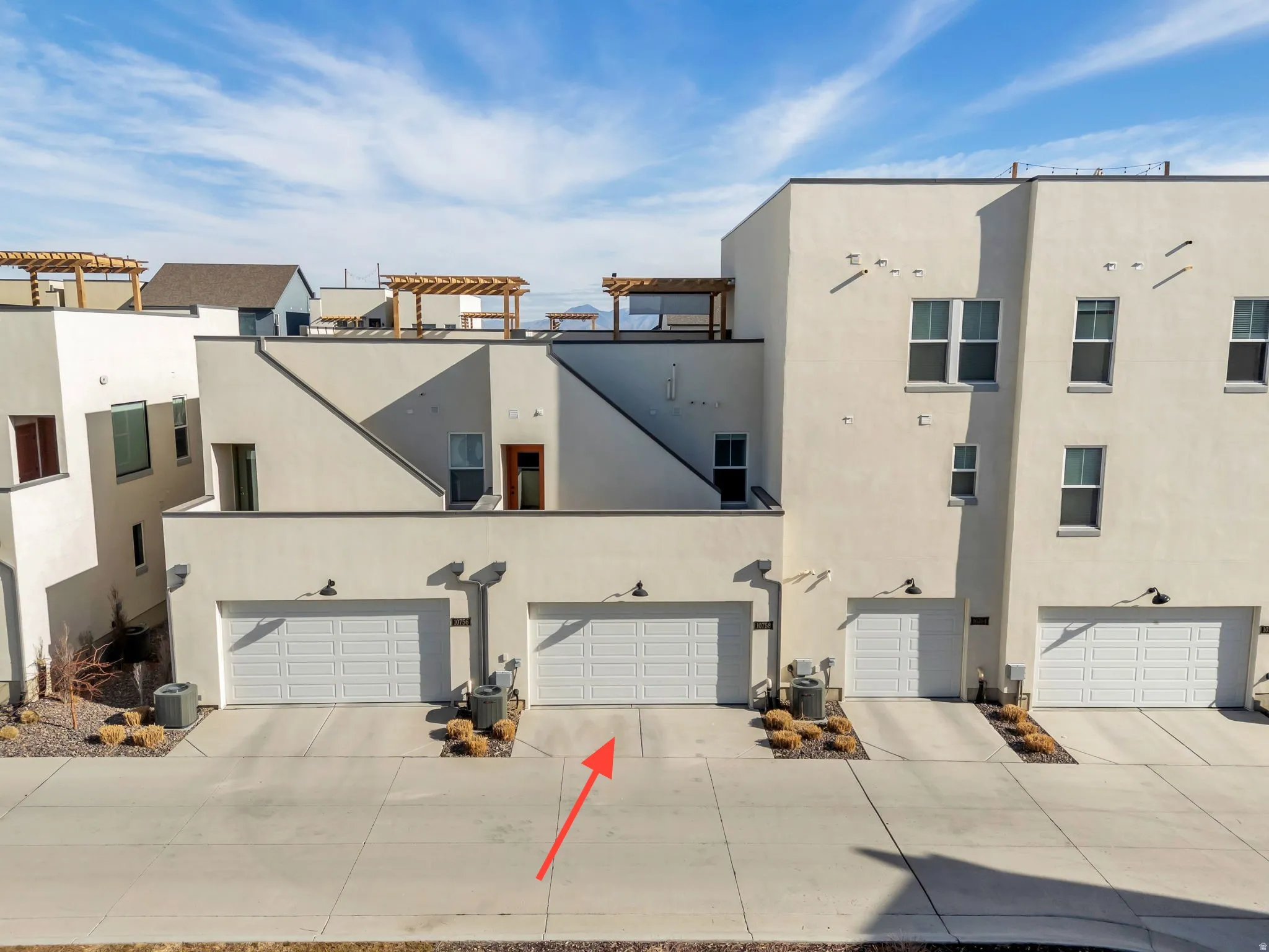 Spacious driveway and two car garage featuring the back patio