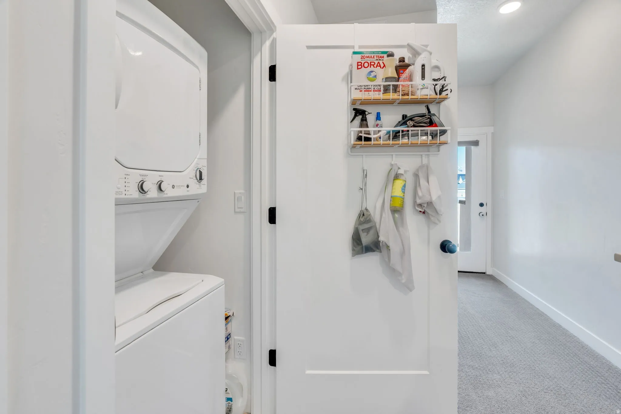 Upstairs laundry closet featuring door to the back deck and rooftop terrace