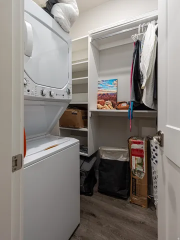 Laundry room featuring stacked washer and clothes dryer and dark wood-style floors