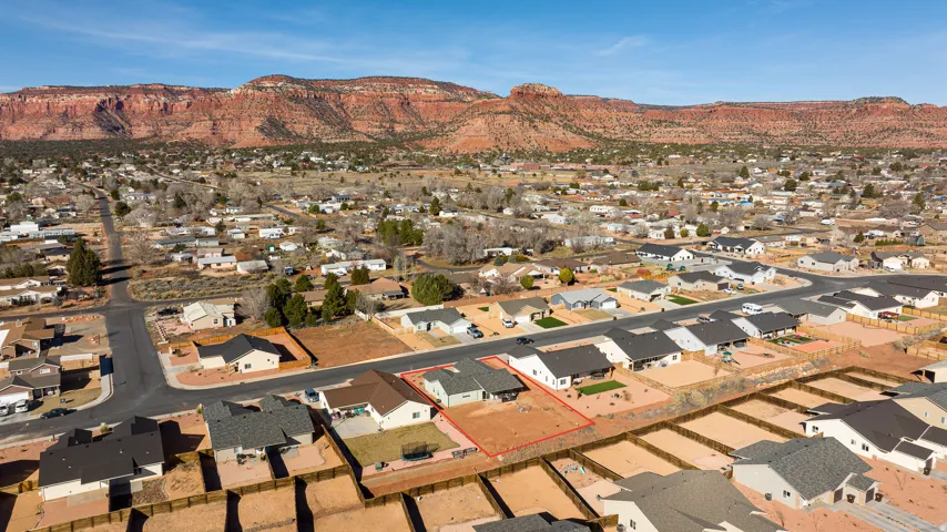 Aerial view of residential area featuring a mountain backdrop and property parcel outlined