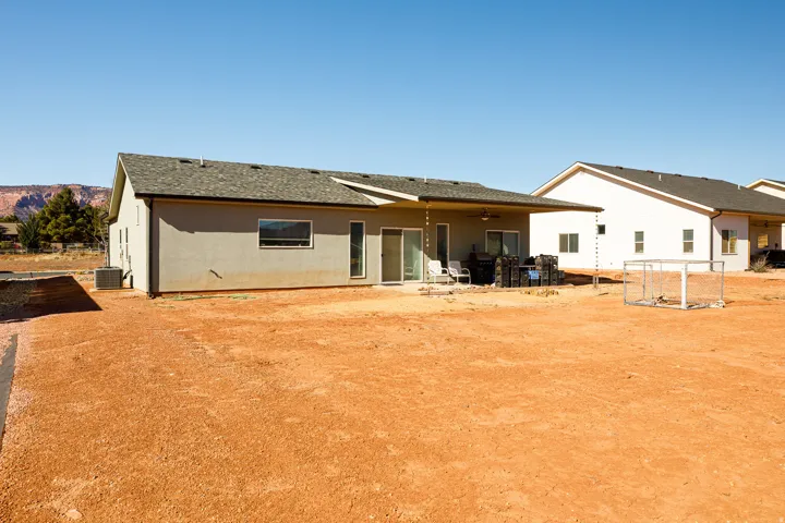 Rear view of property featuring roof with shingles, a patio area, stucco siding, and a ceiling fan