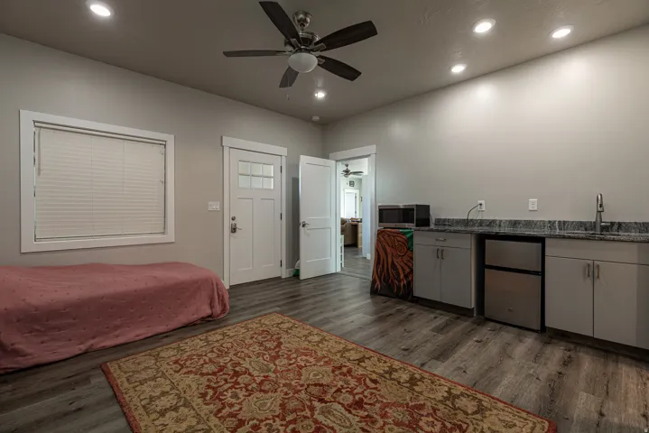 Bedroom with dark wood-style flooring, stainless steel refrigerator, a ceiling fan, and recessed lighting
