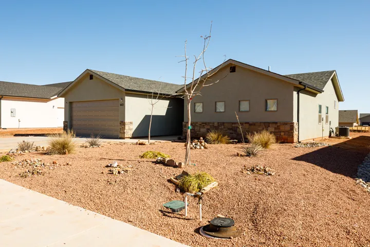 View of front of home featuring stucco siding, concrete driveway, a garage, roof with shingles, and stone siding