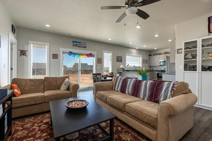 Living area featuring ceiling fan, a textured ceiling, recessed lighting, and dark wood-type flooring