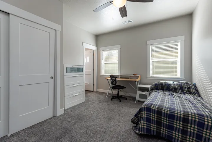 Bedroom with a desk, light carpet, ceiling fan, and a textured ceiling
