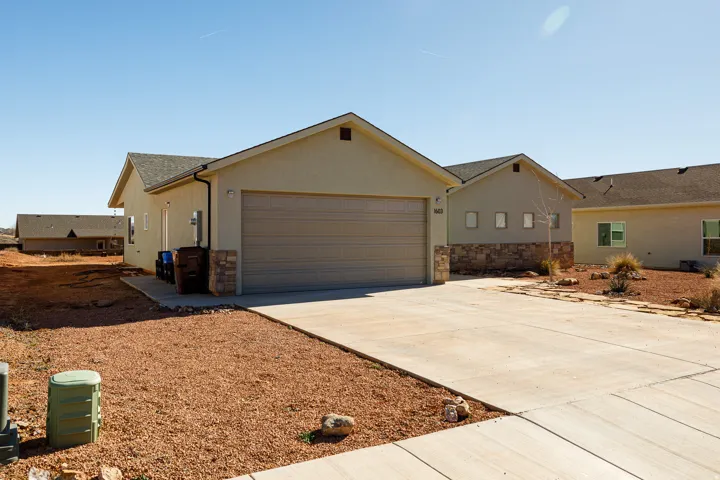 Single story home with stone siding, driveway, stucco siding, an attached garage, and a shingled roof