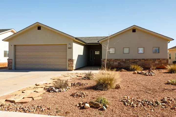 Ranch-style house with driveway, stucco siding, an attached garage, and roof with shingles