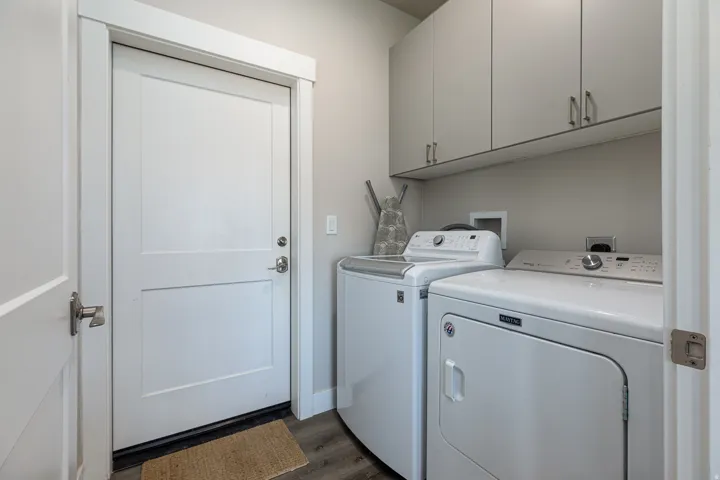 Laundry room featuring dark wood-type flooring, separate washer and dryer, and cabinet space