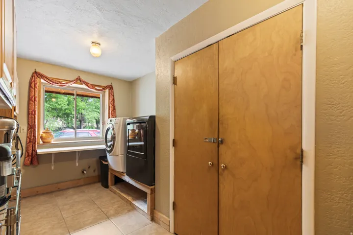 Laundry room with a textured wall, a textured ceiling, light tile patterned floors, and separate washer and dryer