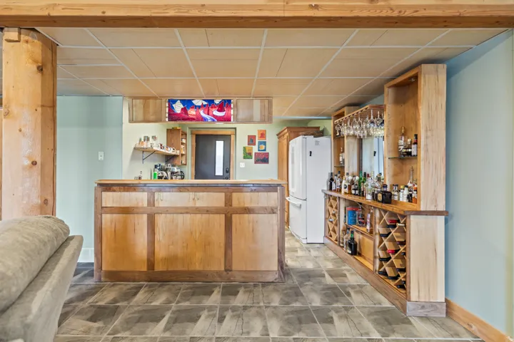 Indoor dry bar with open shelves, freestanding refrigerator, and a paneled ceiling