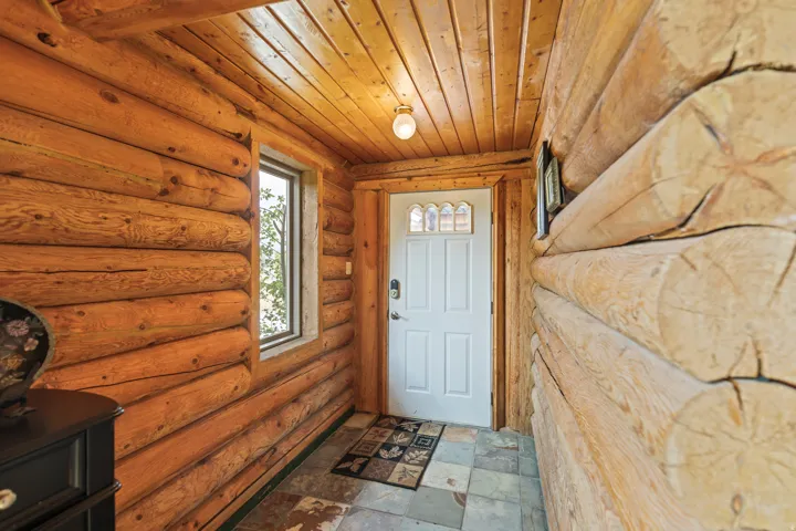 Doorway to outside featuring wooden ceiling, rustic walls, and stone tile floors