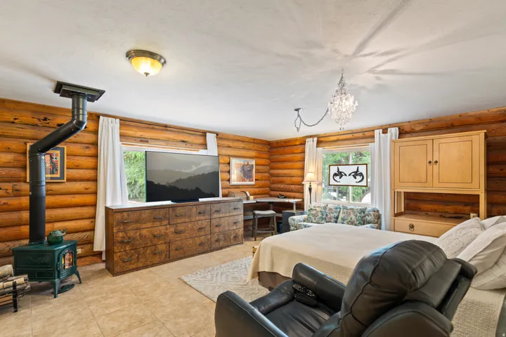 Bedroom featuring rustic walls, a wood stove, and suspended lighting