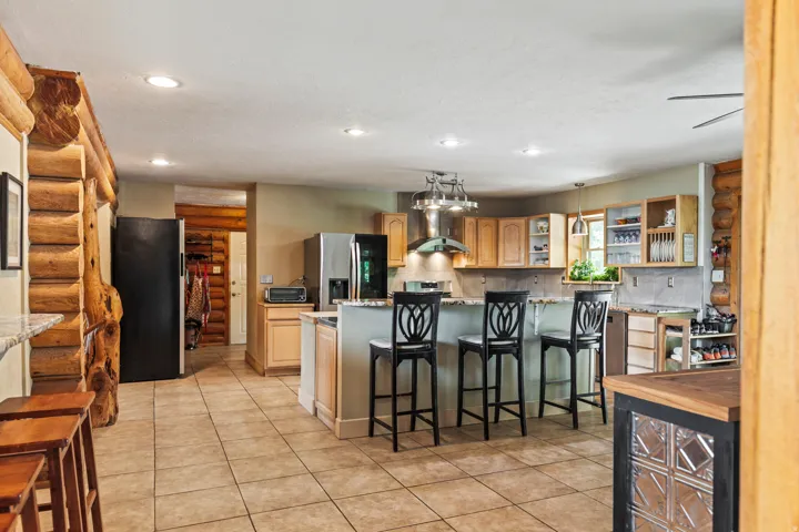 Kitchen with log walls, open shelves, a breakfast bar area, freestanding refrigerator, and light wood finish cabinetry