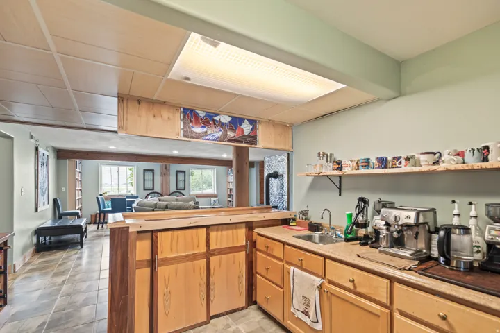 Kitchen featuring a peninsula, light countertops, open floor plan, light wood finish cabinets, and open shelves