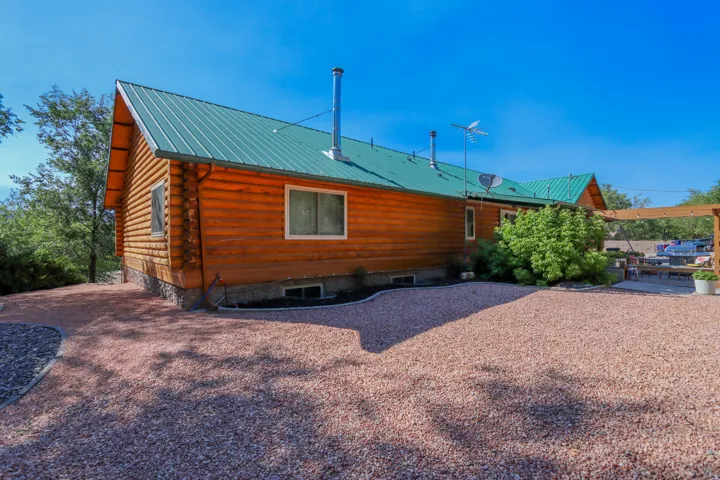 Log cabin exterior with a green metal roof and a light-colored gravel yard