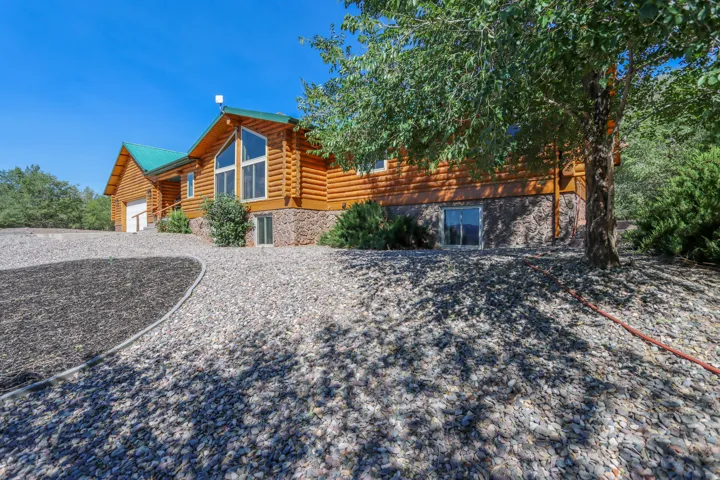 Log-style exterior featuring a green metal roof and a stone foundation