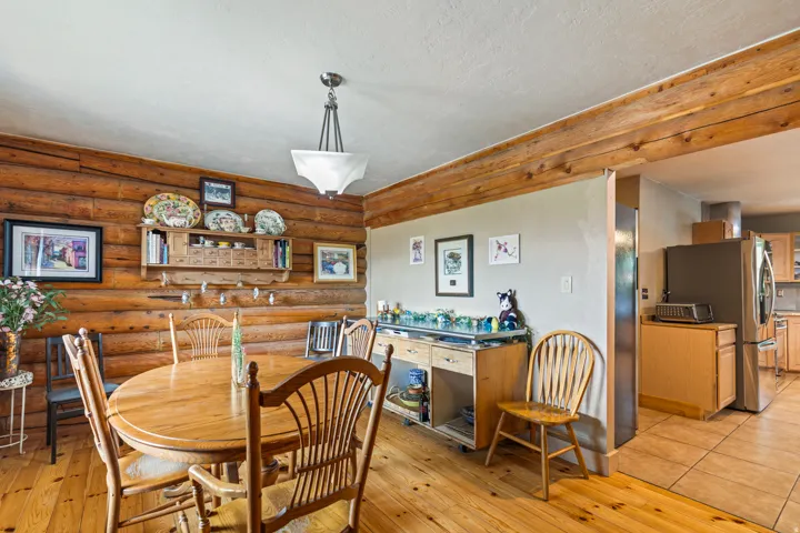 Dining area with log walls, light wood finished floors, and a textured ceiling