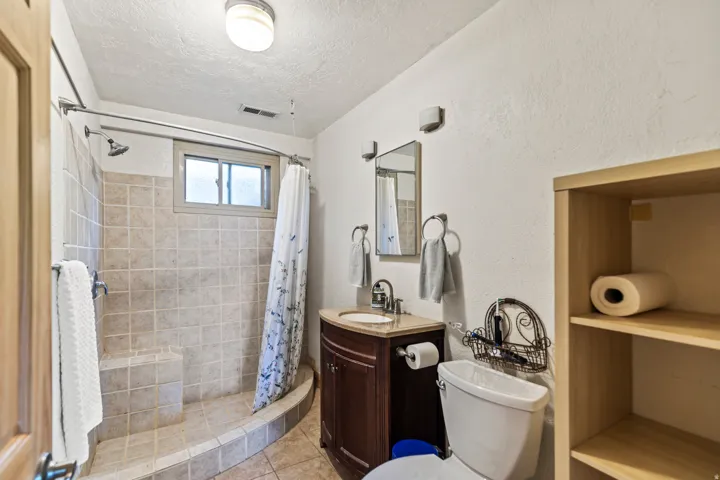 Bathroom with vanity, a textured ceiling, a shower stall, and light tile patterned flooring