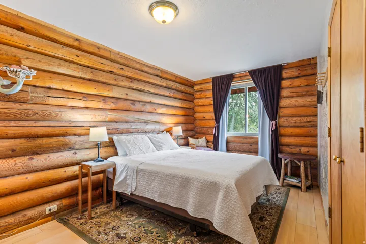 Bedroom featuring log walls and light wood-type flooring