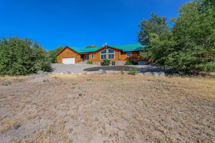 Log home exterior featuring a vibrant green roof, wood siding, and an attached two-car garage