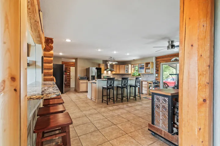 Kitchen with a breakfast bar, light countertops, log walls, recessed lighting, and freestanding refrigerator