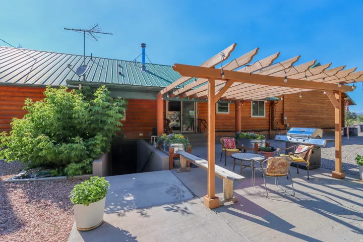 Outdoor patio featuring a wooden pergola with string lights, a concrete surface, and gravel landscaping
