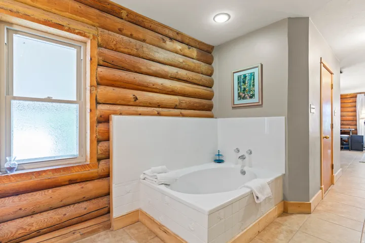 Full bath with rustic walls, a bath, and light tile patterned floors