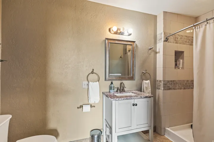Full bath featuring a stall shower, vanity, and a textured wall