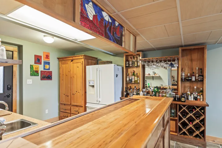 Indoor wet bar with wooden counters, white fridge with ice dispenser, and wood finish cabinetry