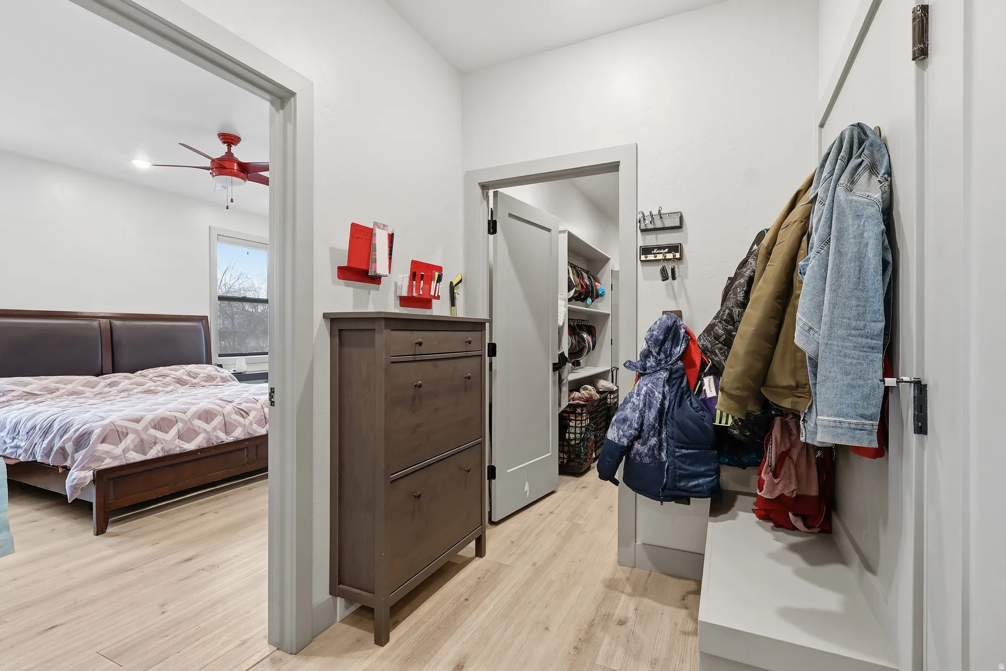 Drop zone with doggy door to garage light wood-type flooring and ceiling fan