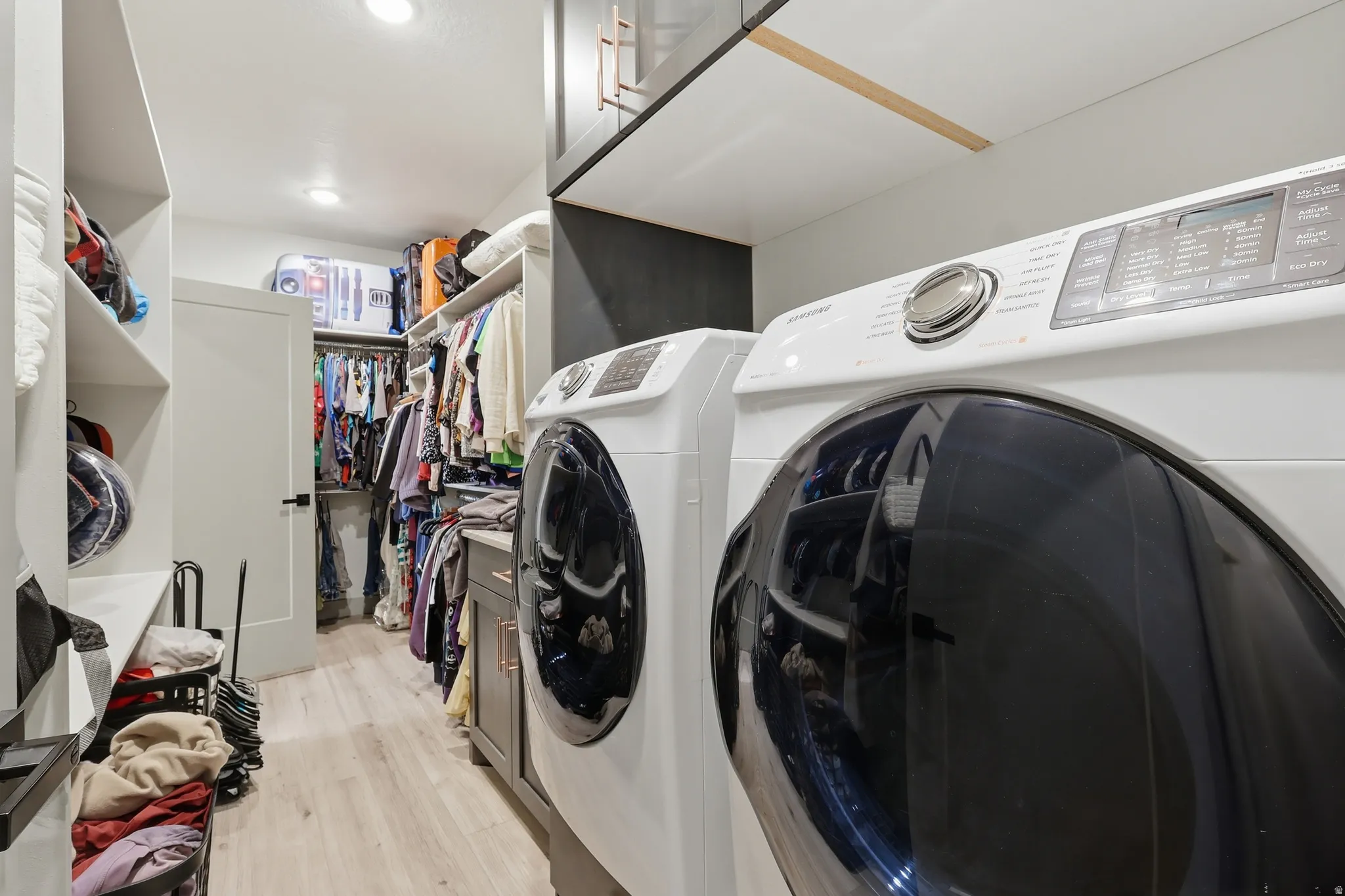Master Bedroom Closet and Laundry area with light wood finished floors, cabinet space, and washer and dryer