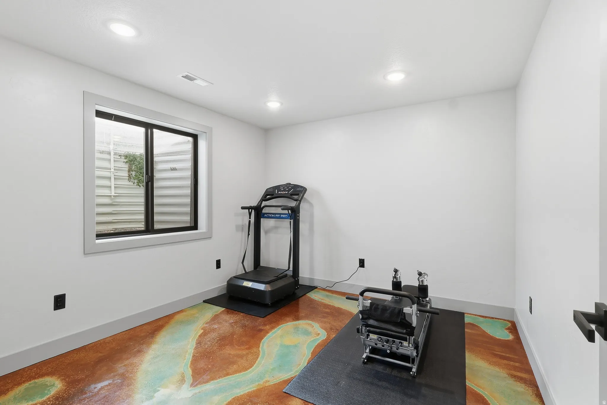 Bedroom used as an exercise area with recessed lighting and finished concrete floors